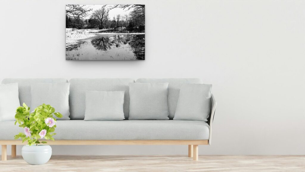 Plan d’eau enneigé, reflets d’arbres, tableau sur aluminium 100 × 70 cm au-dessus d’un canapé (mise en situation)