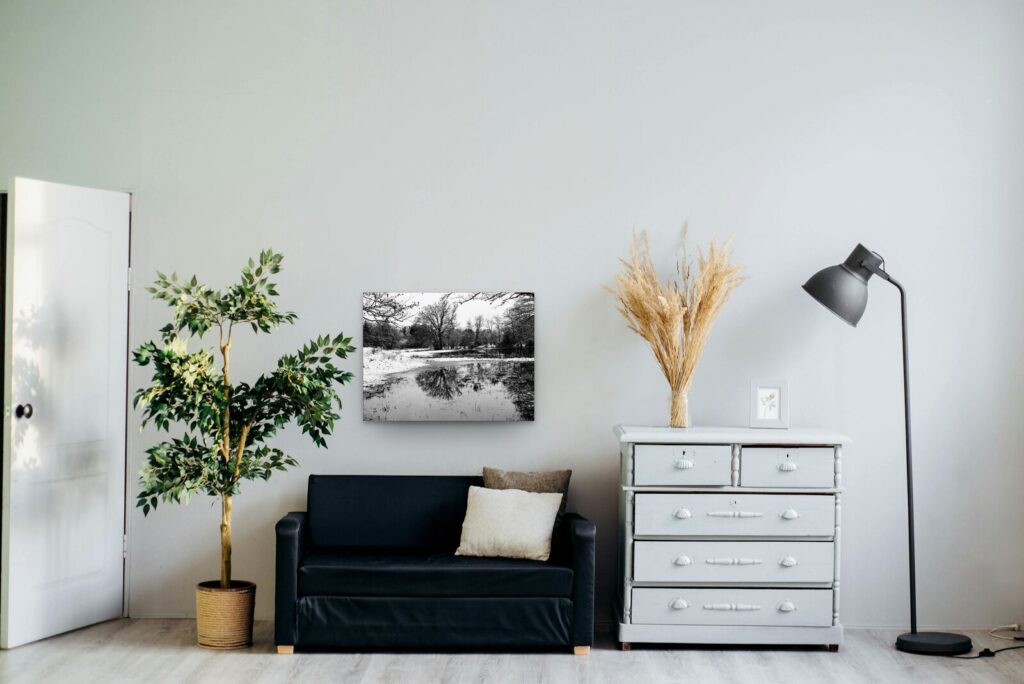 Plan d’eau enneigé, reflets d’arbres, tableau sur aluminium 80 × 60 cm dans un salon clair (mise en situation)