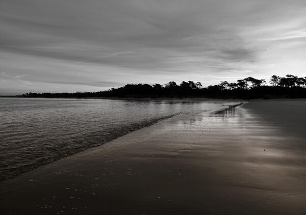 Grève mouillée au soleil couchant, tableau plage en noir et blanc