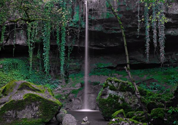 Cascade sous un surplomb moussu, tableau cascade dans un sous-bois