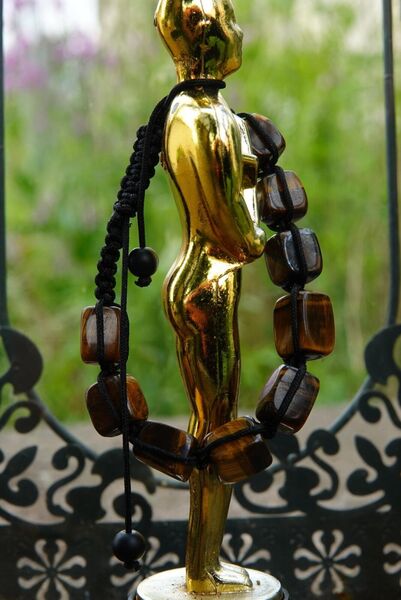 Liens sacrés, tableau statuette dorée et bracelet de perles