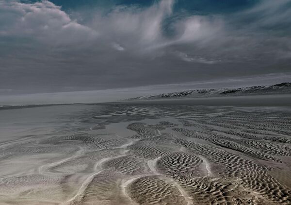 Sable ridé et ciel d’orage sur la côte, tableau plage à marée basse